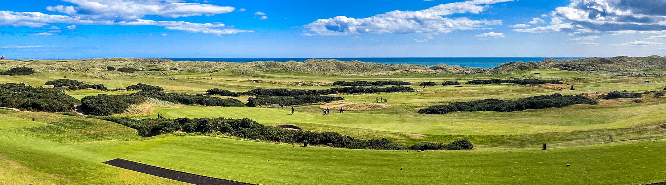 Scenic view of a golf course with green grass and blue sky.
