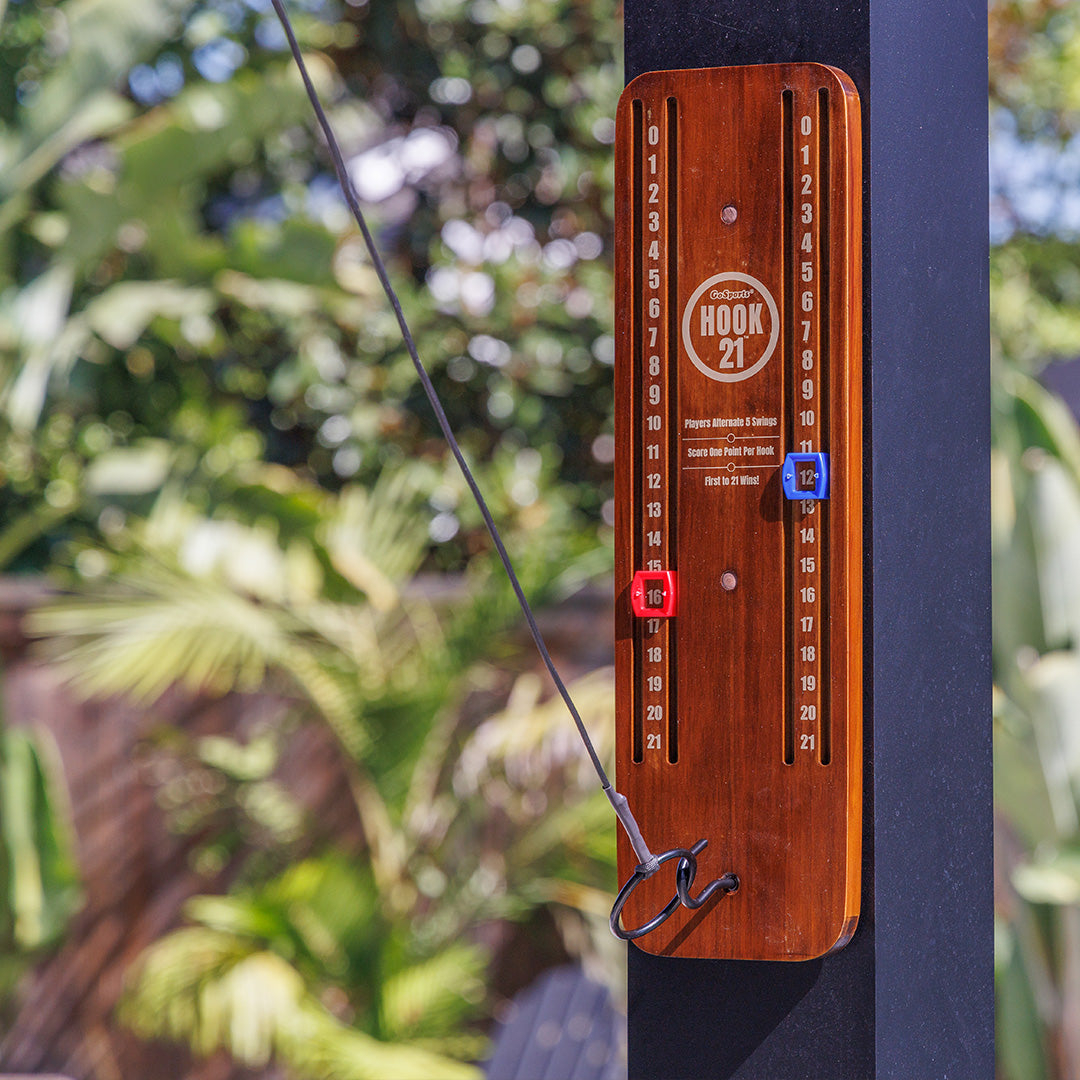 Wooden placard with words 'HOOK 21' with a ring and line with measurement markings against a blurred green outdoor background