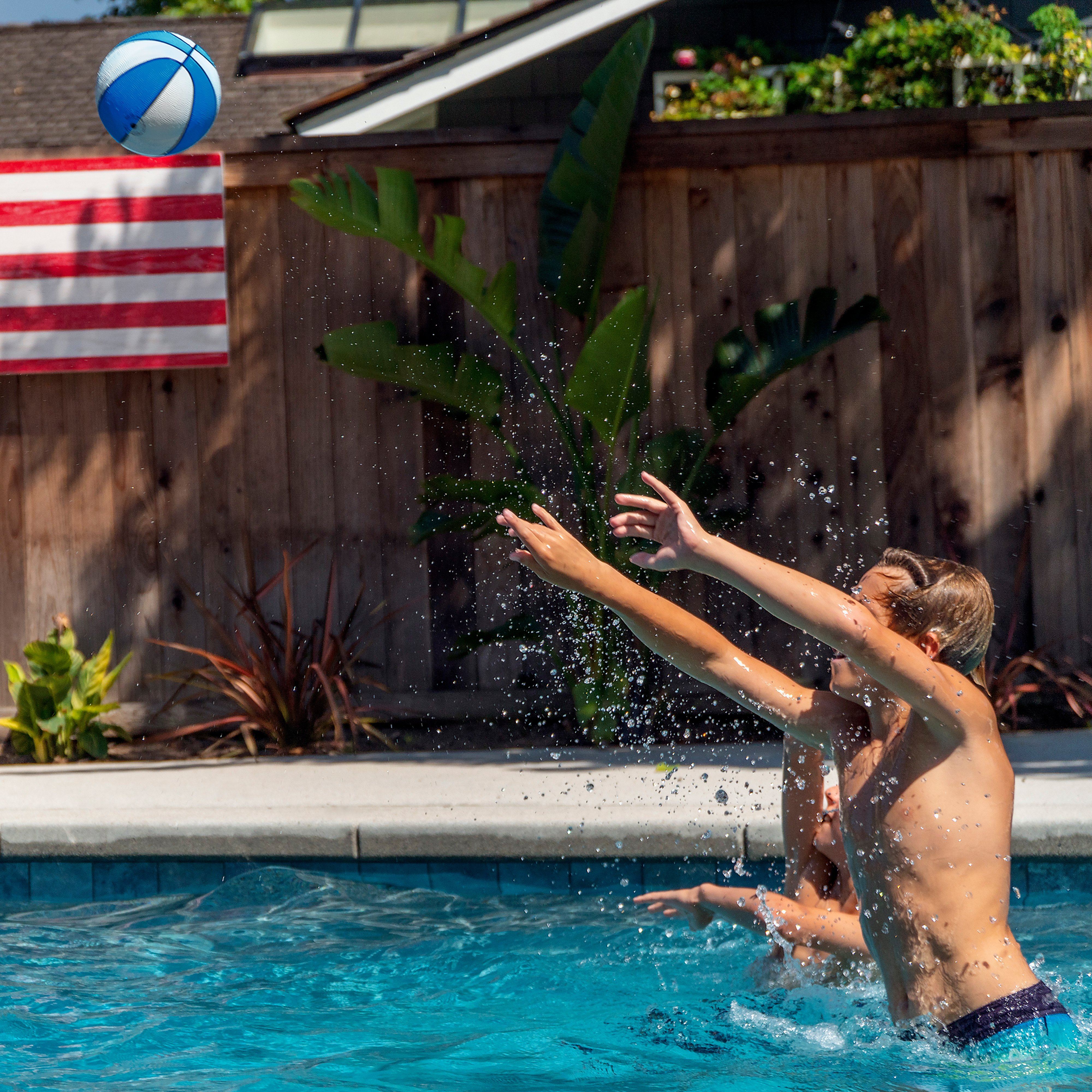 a boy playing with a ball in a pool