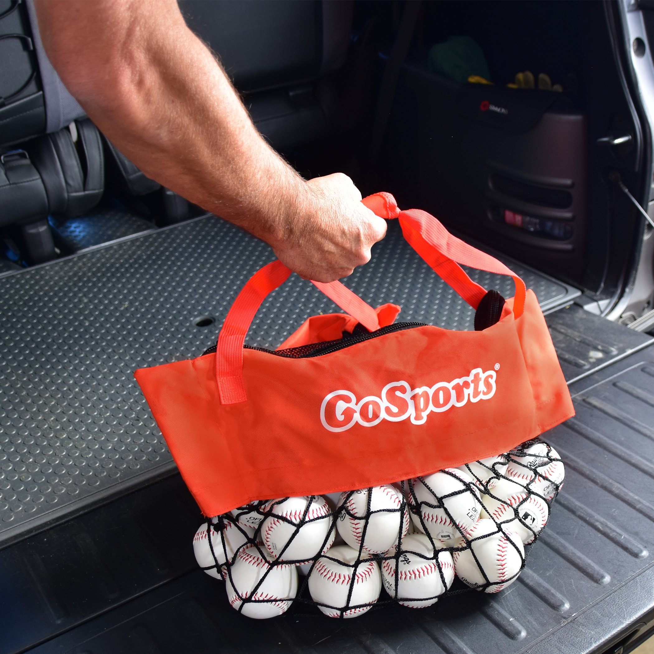 a man putting a bag of baseballs into the back of a car