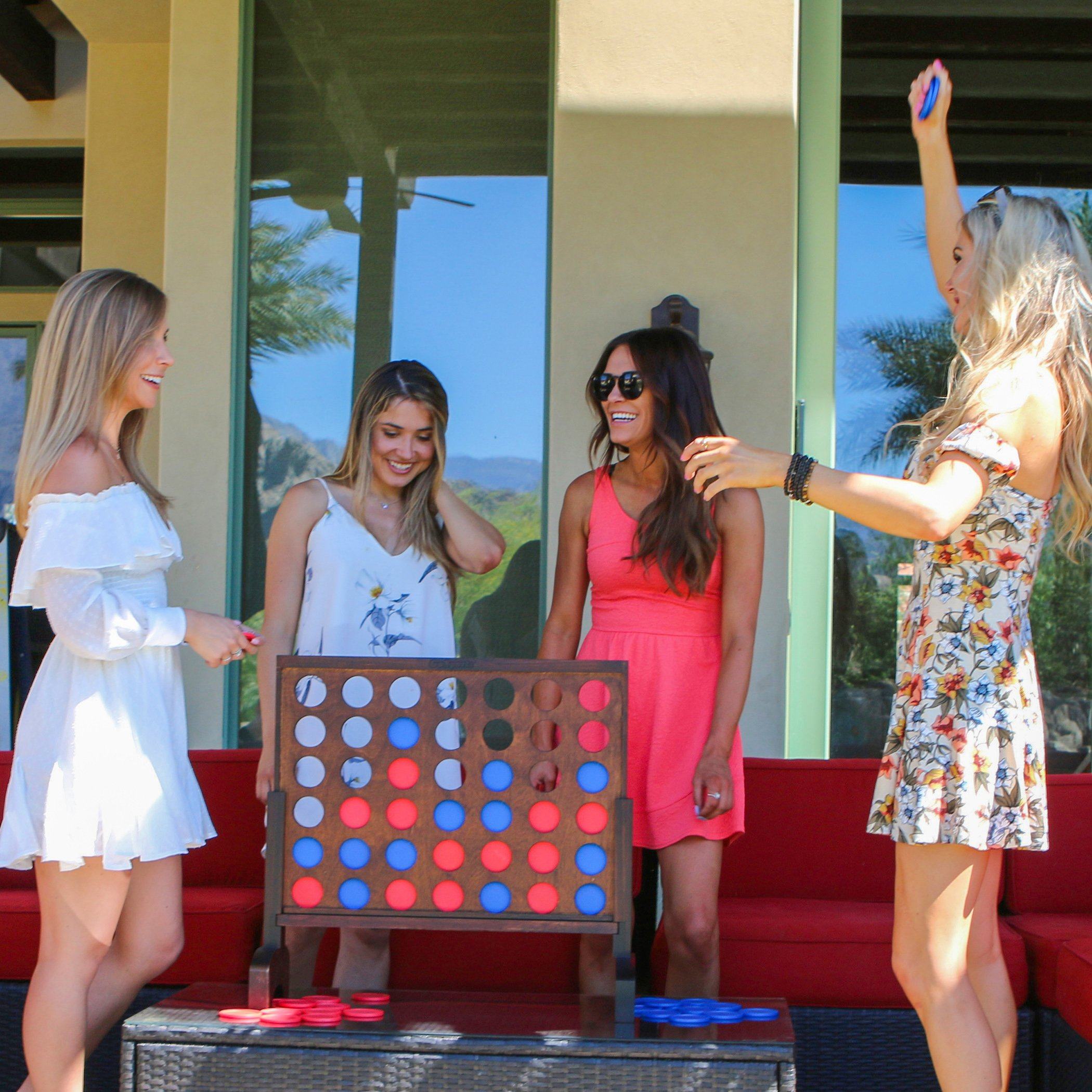 a group of women standing around a giant four - sided game