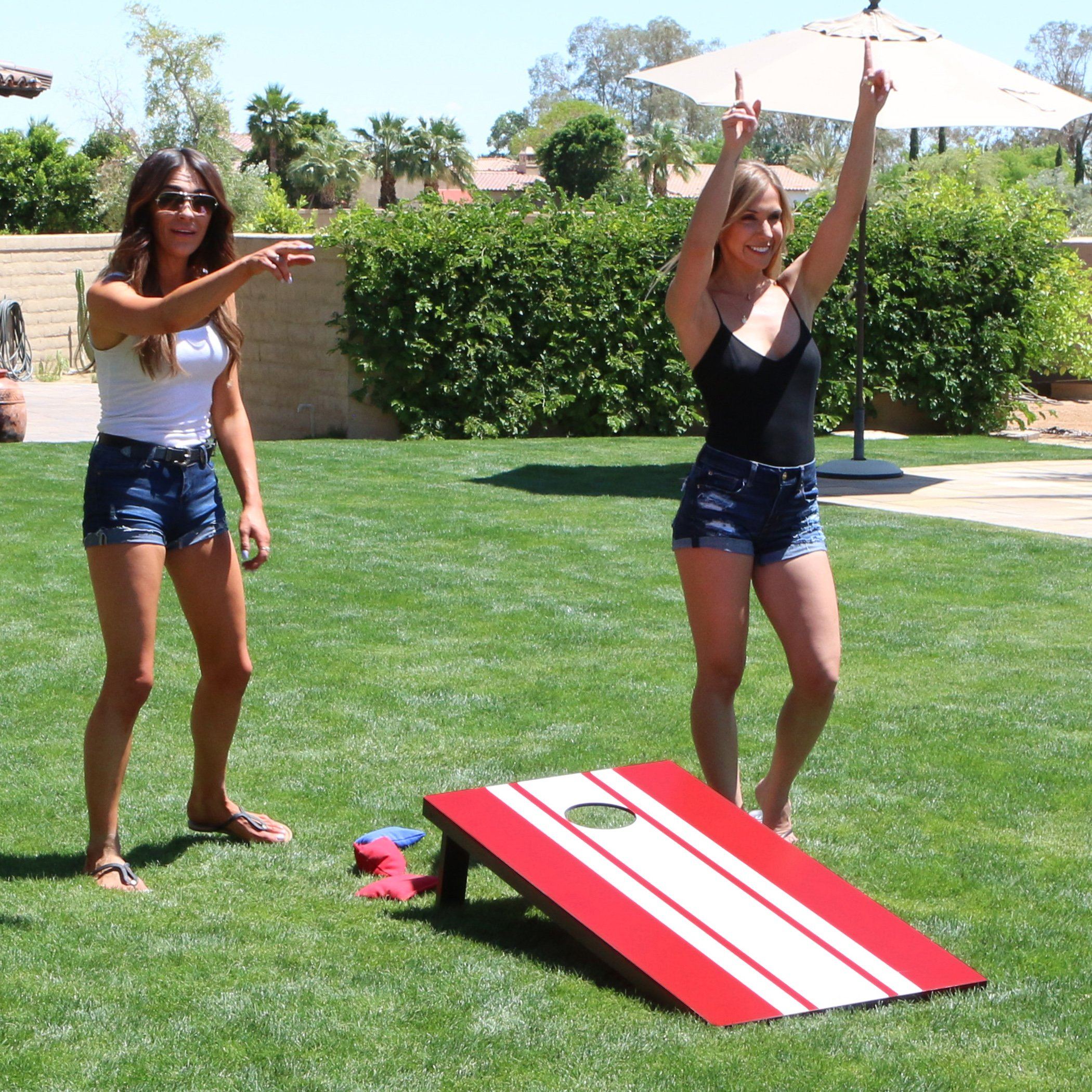 two women playing corno game in the backyard