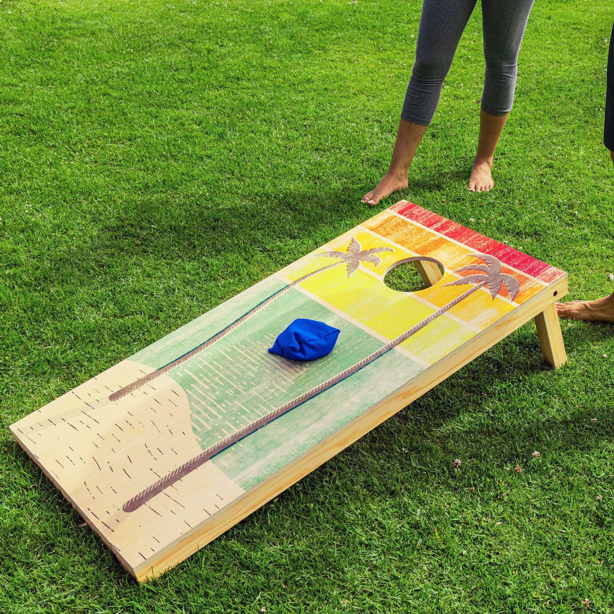 a woman standing next to a giant cornhole game