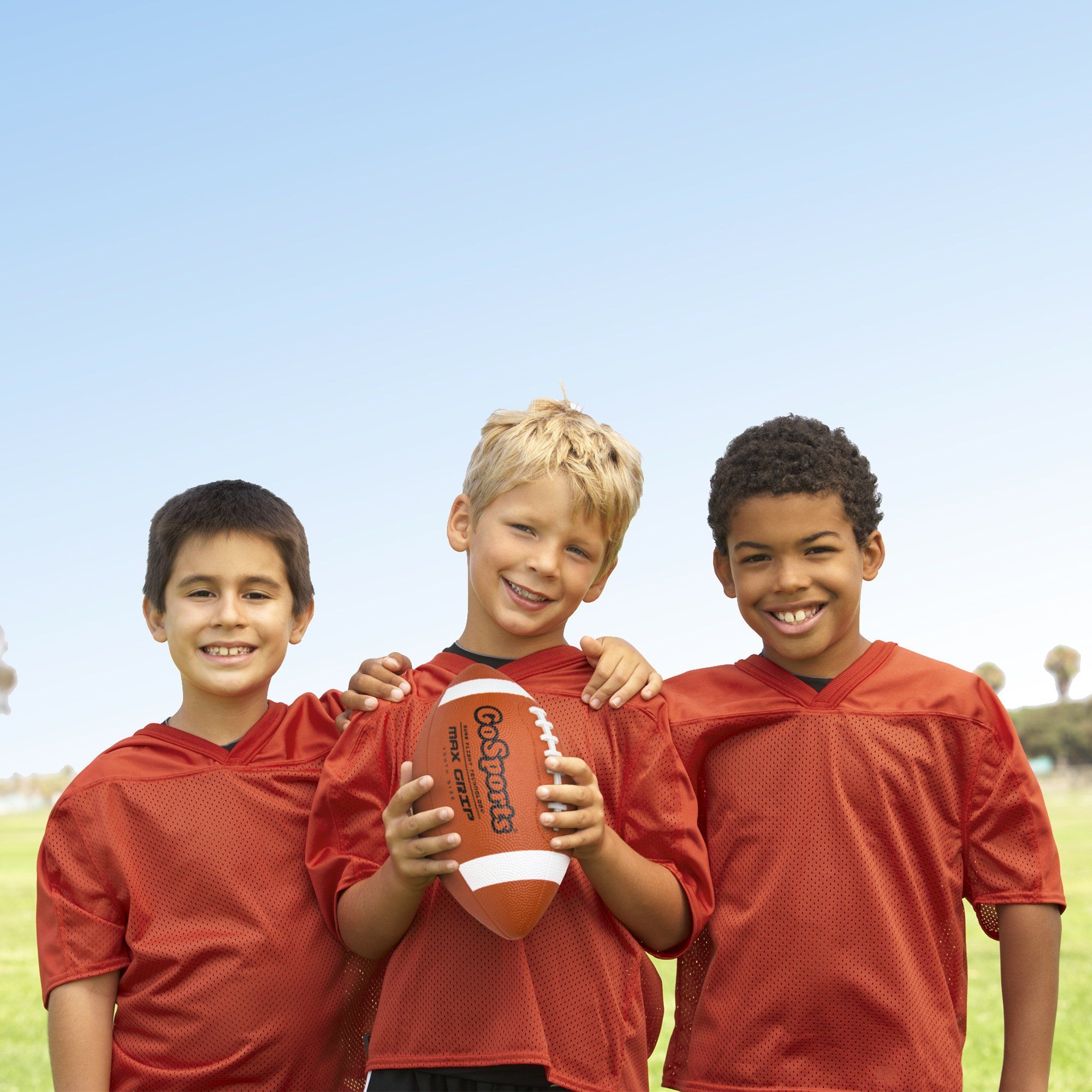 three boys in red jerseys holding a football