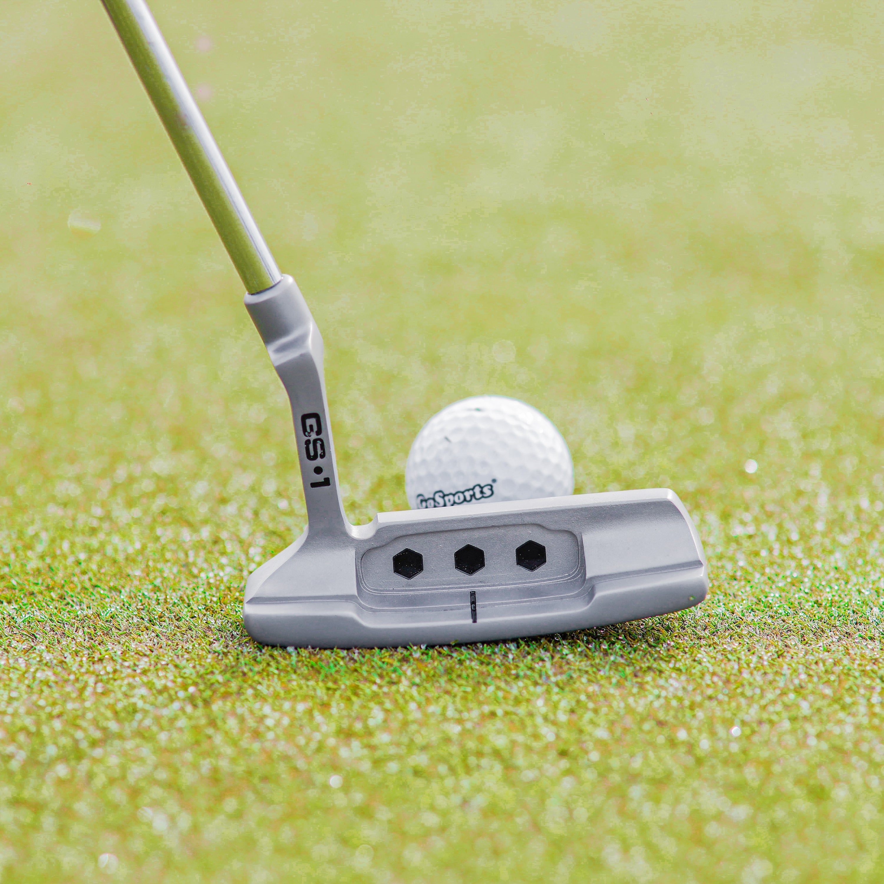 a golf ball and putter on a green field