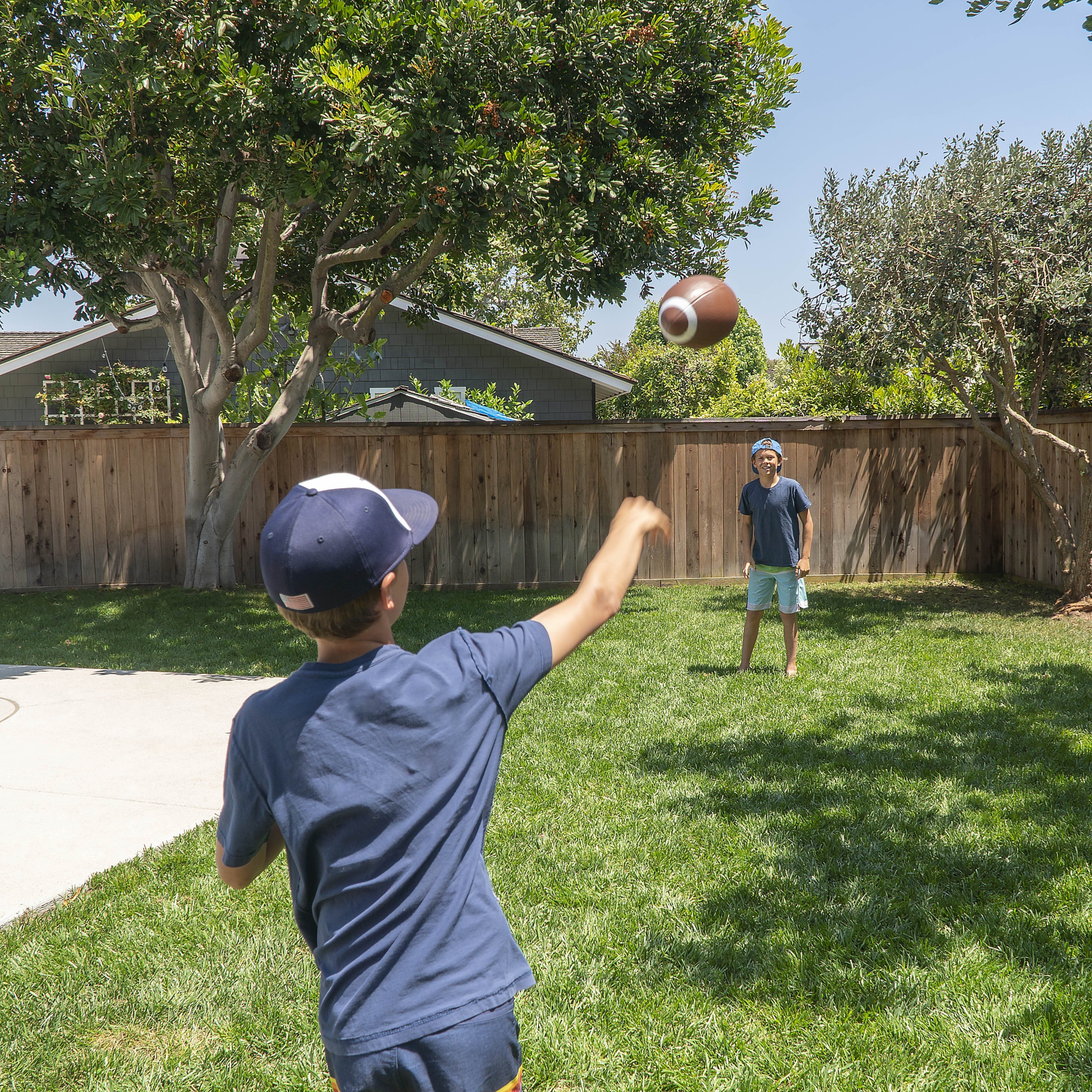 a boy throwing a ball in a backyard
