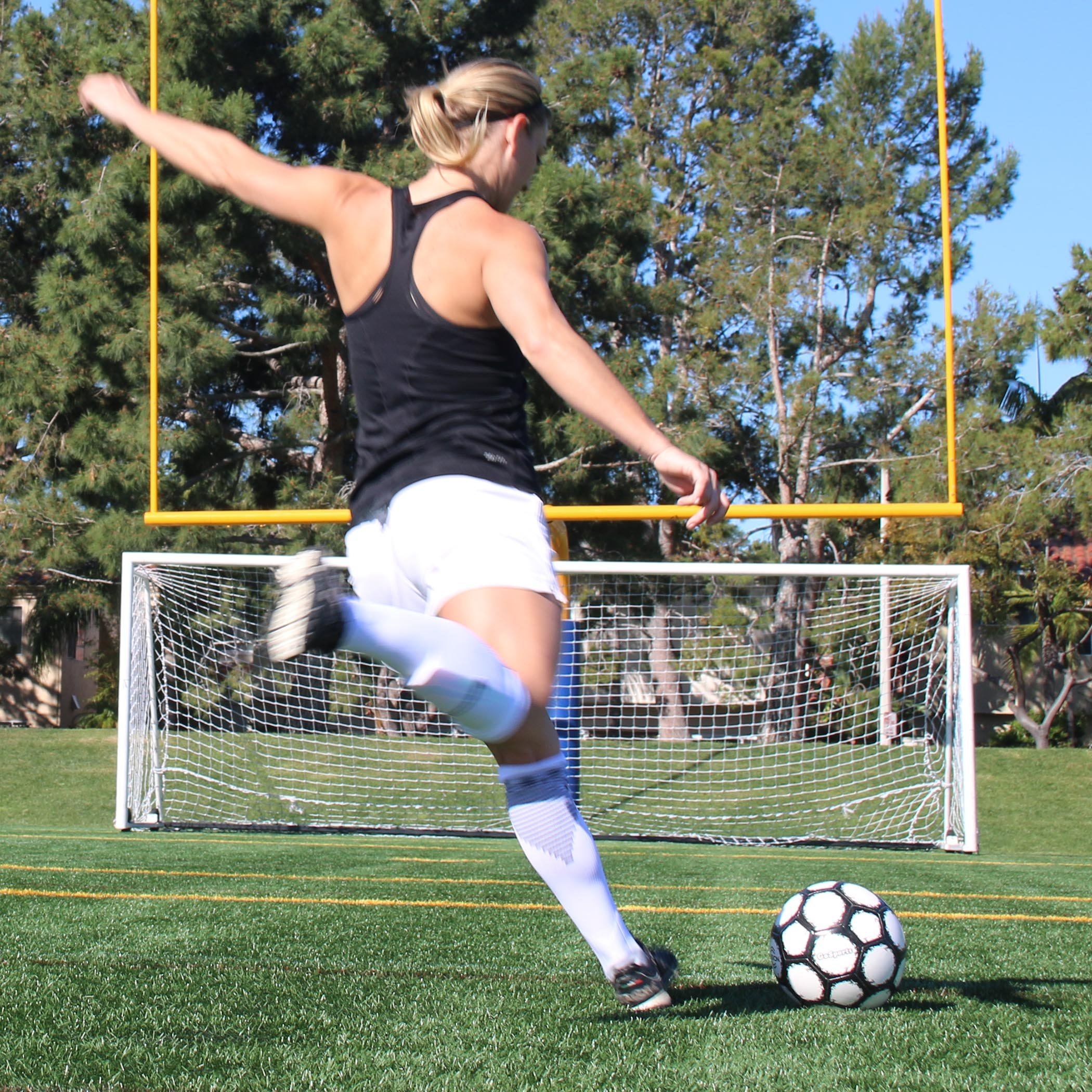a woman kicking a soccer ball on a field