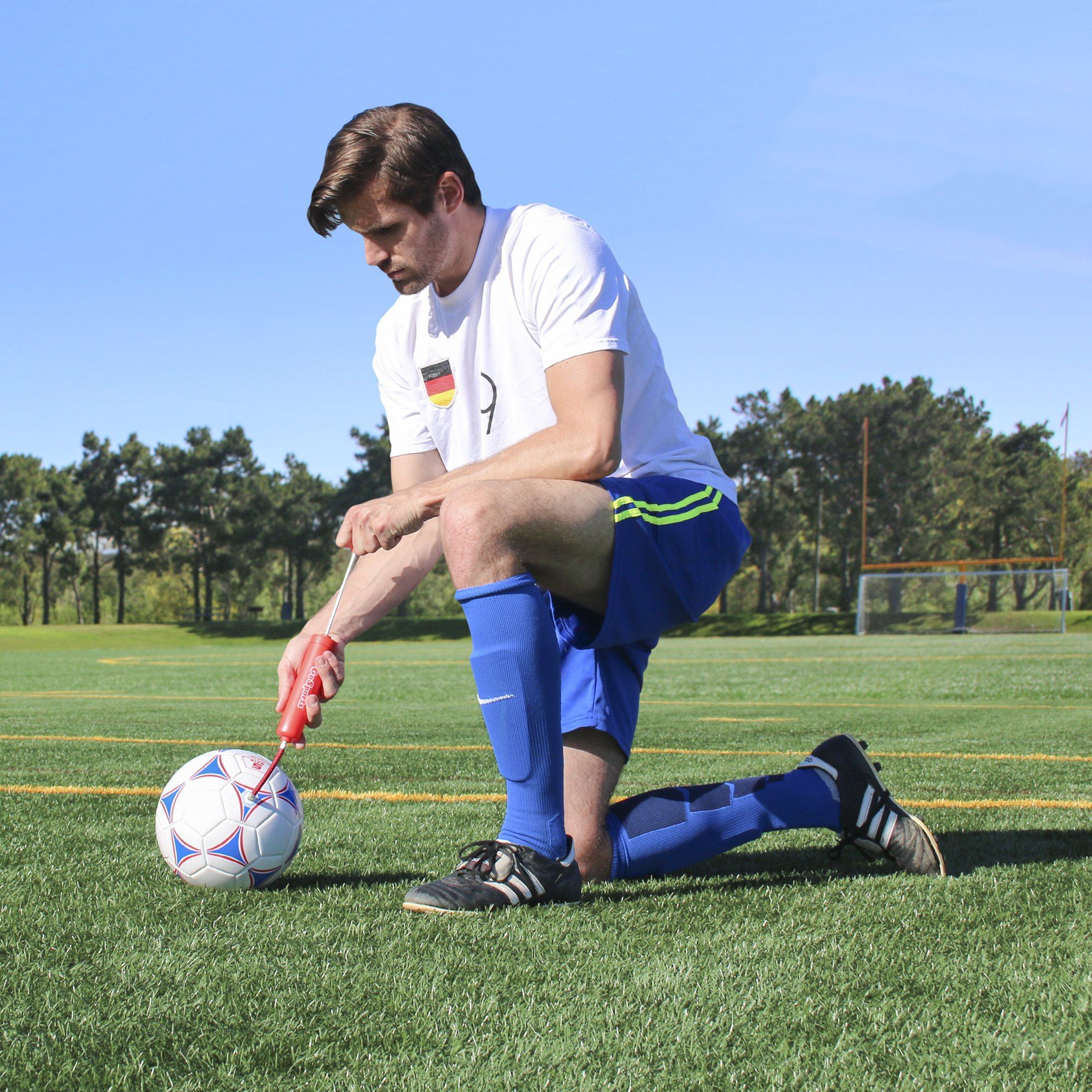 a man kneeling on the grass with a soccer ball