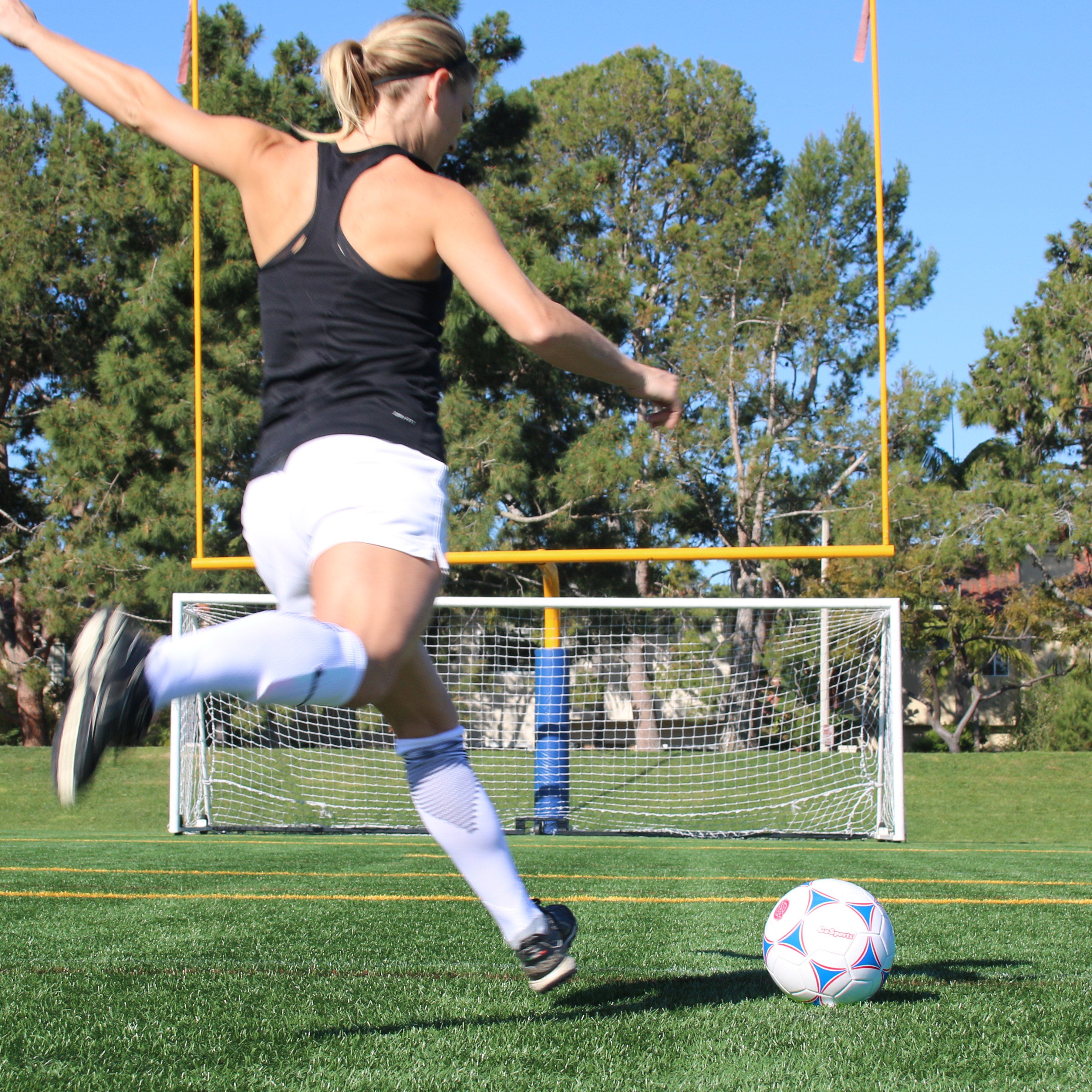 a woman kicking a soccer ball on a field