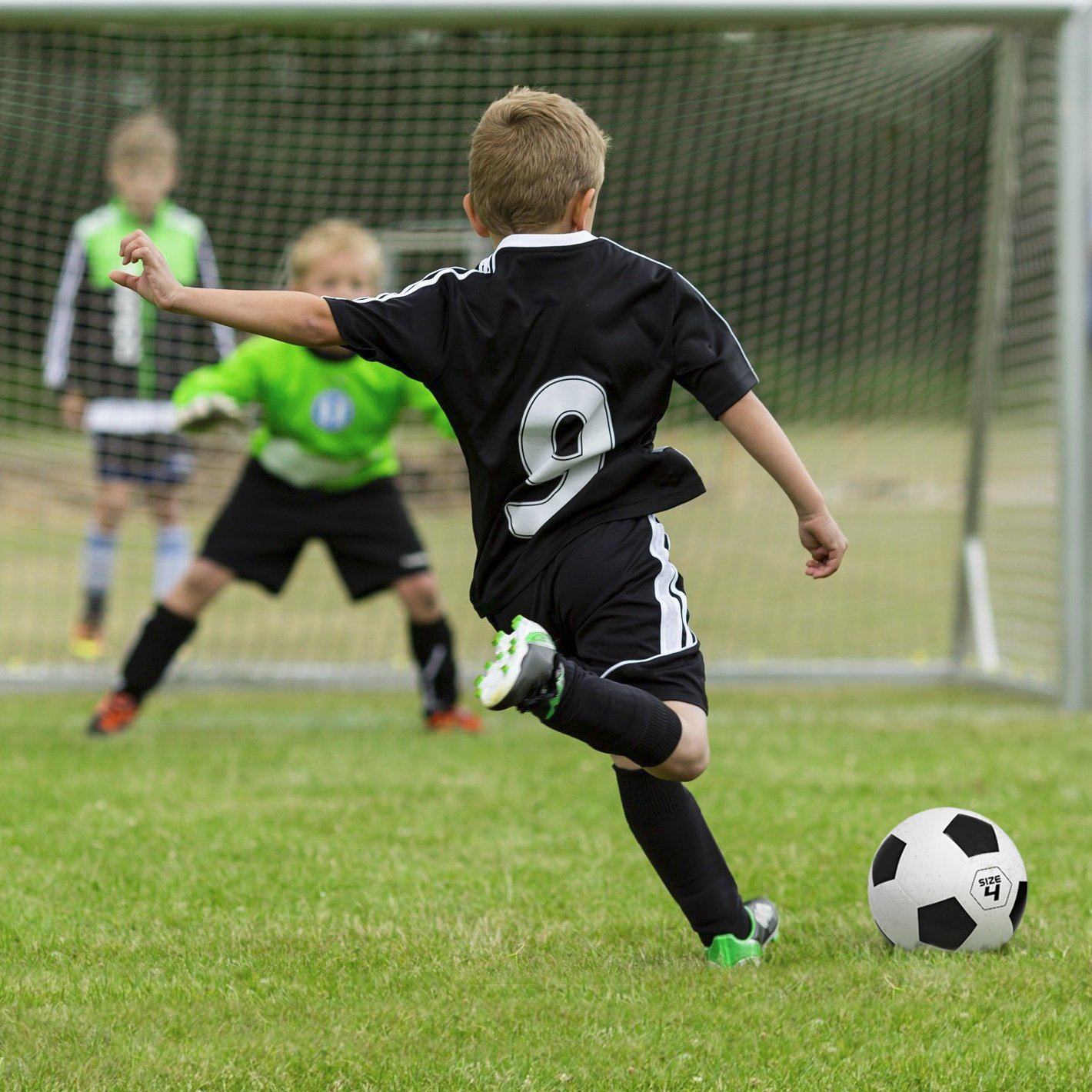 a boy kicking a soccer ball on a field