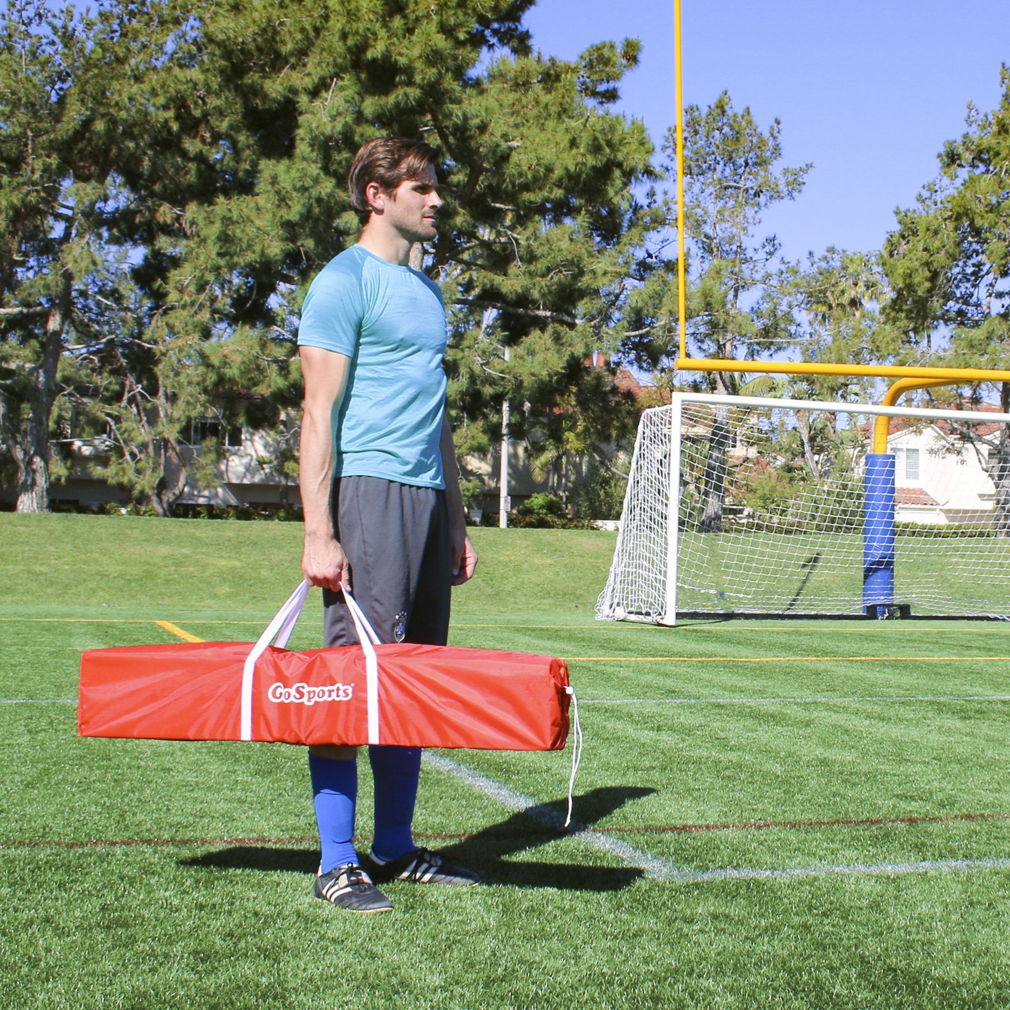 a man holding a red bag on a soccer field