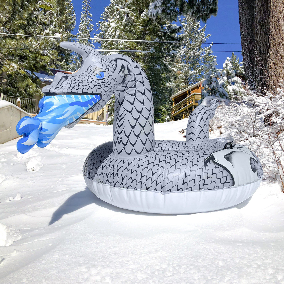 Front view of the GoSports Ice Dragon snow tube's dragon head breathing blue frost fire in a snowy yard