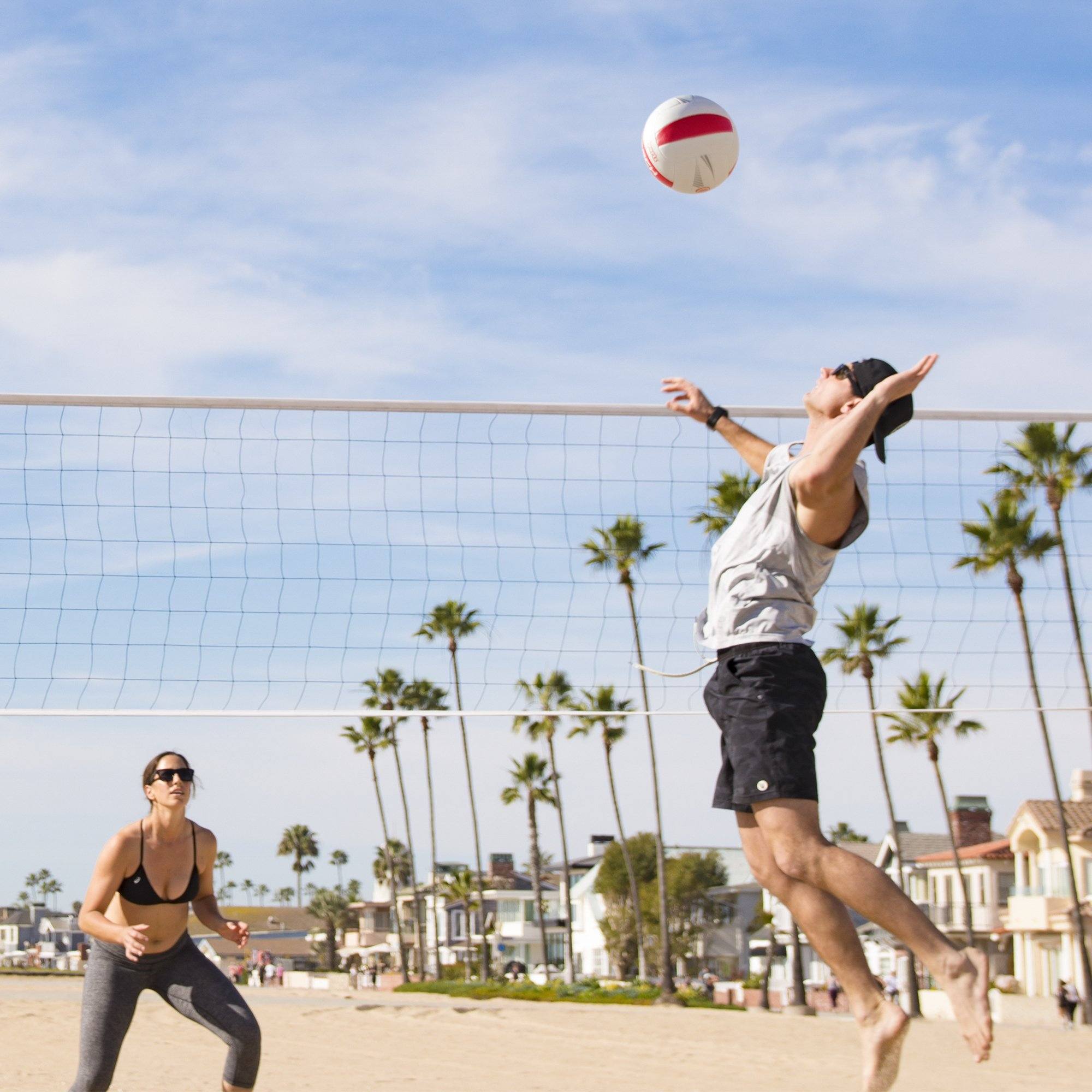 a man and woman playing volleyball on the beach
